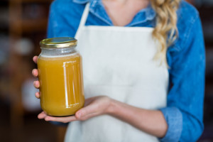 Mid-section of female staff holding jar of honey